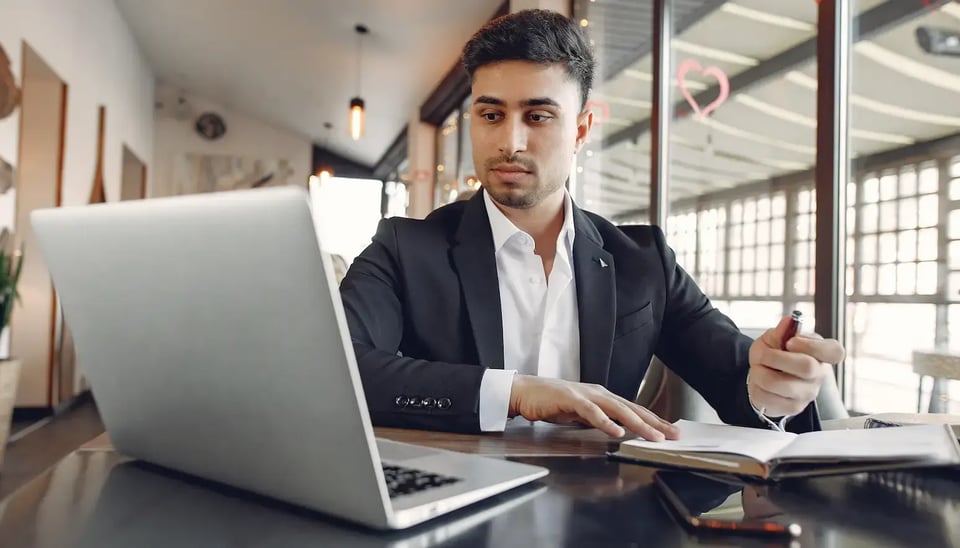 Homem caucasiano com roupa social em frente a um computador